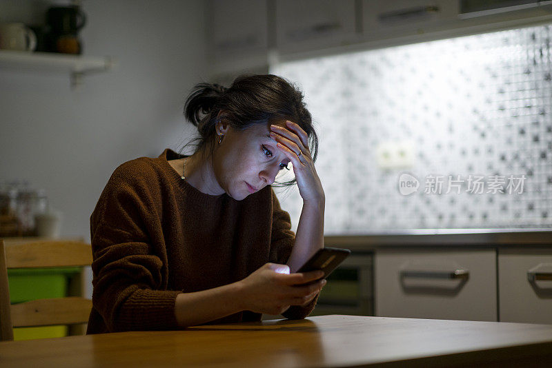 晚上在家看手机屏幕的女人感到心烦意乱。