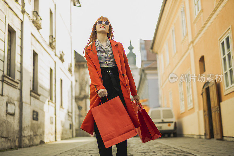 红发女孩在城里拎着购物袋