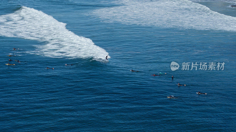 孤独的冲浪者乘着波浪穿过人群