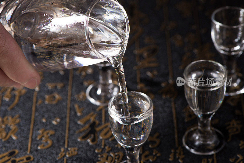 烈酒或烈性酒是从一个瓶子的背景倒进玻璃杯