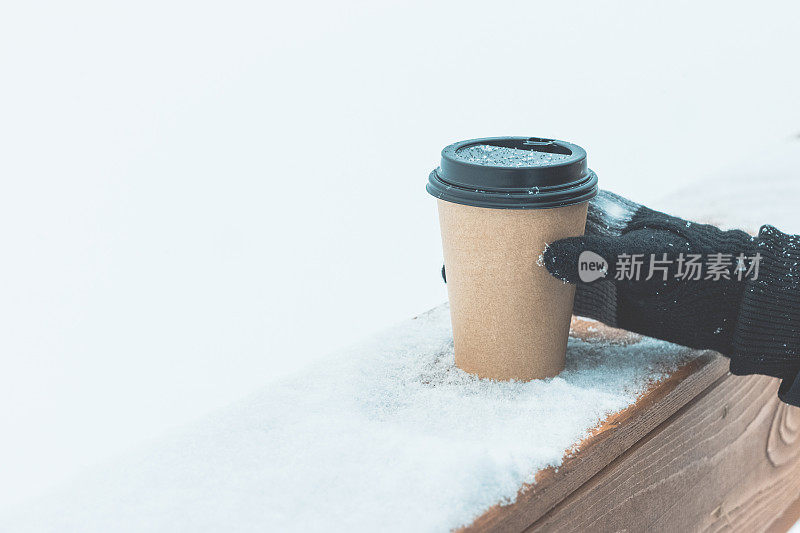 一个一次性咖啡杯放在雪地上的木板上