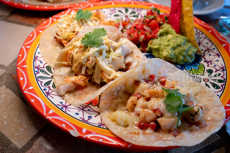 正宗的墨西哥食物，在木制的背景上放着三个墨西哥卷饼架，香菜、番茄、洋葱和酸橙