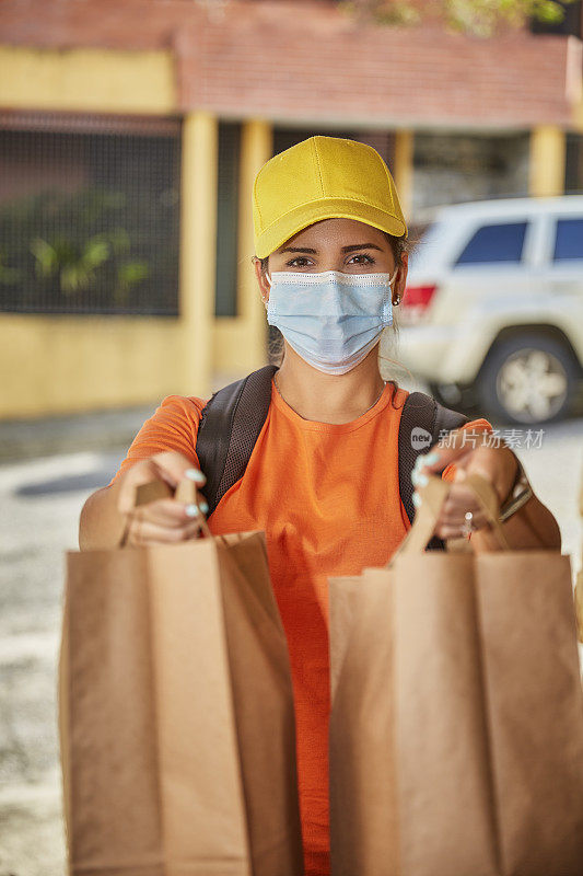 西班牙裔年轻女子送食品和杂货前门的居民客户