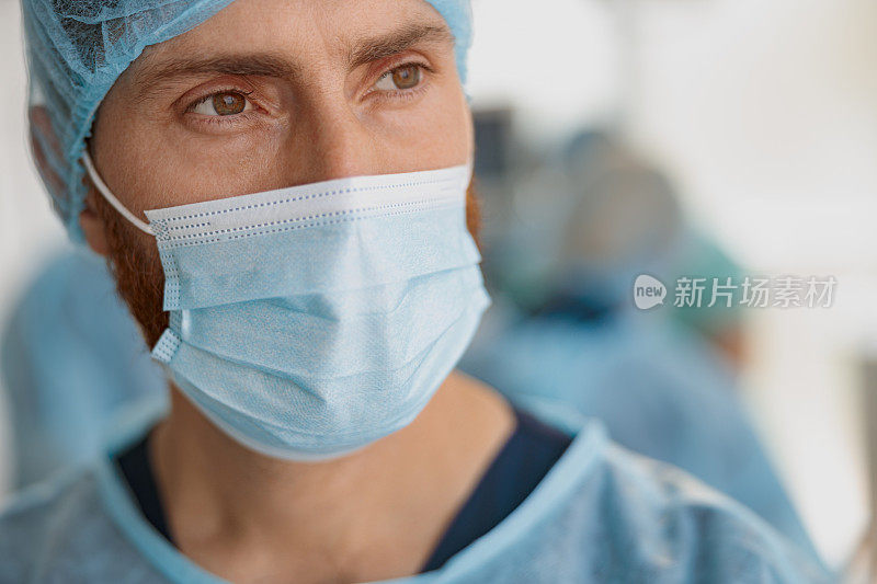 戴口罩的专业医生在手术前站在手术室，看向别处的特写