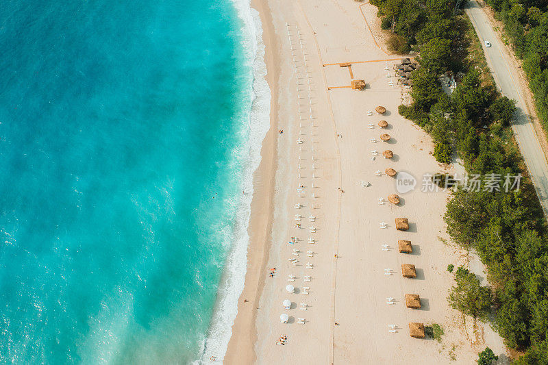 在土耳其的Oludeniz，打着遮阳伞的梦幻般的绿松石海滩鸟瞰图