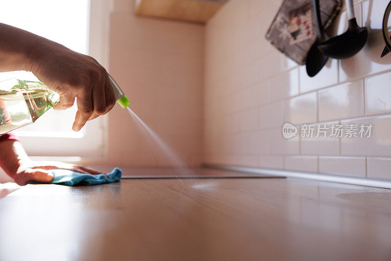 用手在厨房台面喷洒清洁剂，用抹布擦拭