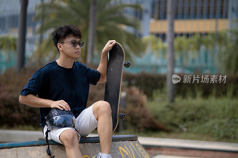 亚洲中国少年在滑板公园休息