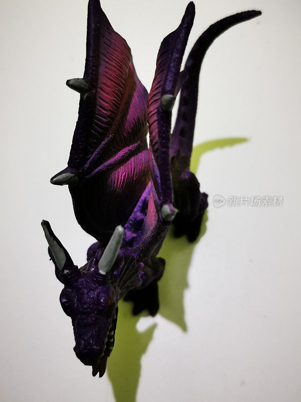 龙形玩具是紫色的，白色的背景上有两个白色的角