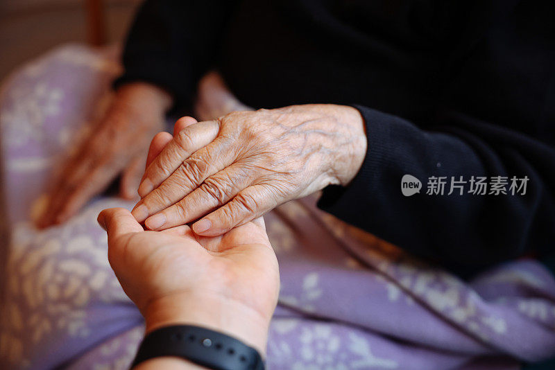 老女人的手牵着年轻女人的手，伸出援手，照顾老人的理念。