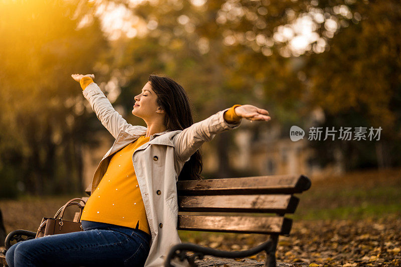 一位孕妇在美丽的秋日在公园里享受。