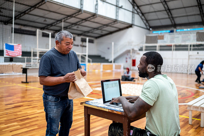 一名士兵在难民避难所使用笔记本电脑与一名残疾难民交谈