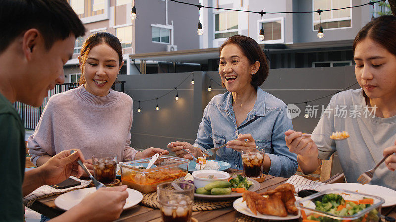 妈妈喜欢泰国菜烹饪家庭日见面，在家吃饭，在餐桌舒适的露台。小组亚洲人年轻的成年男人女人朋友乐趣快乐放松温暖的夜晚野餐和妈妈吃美味的食物。