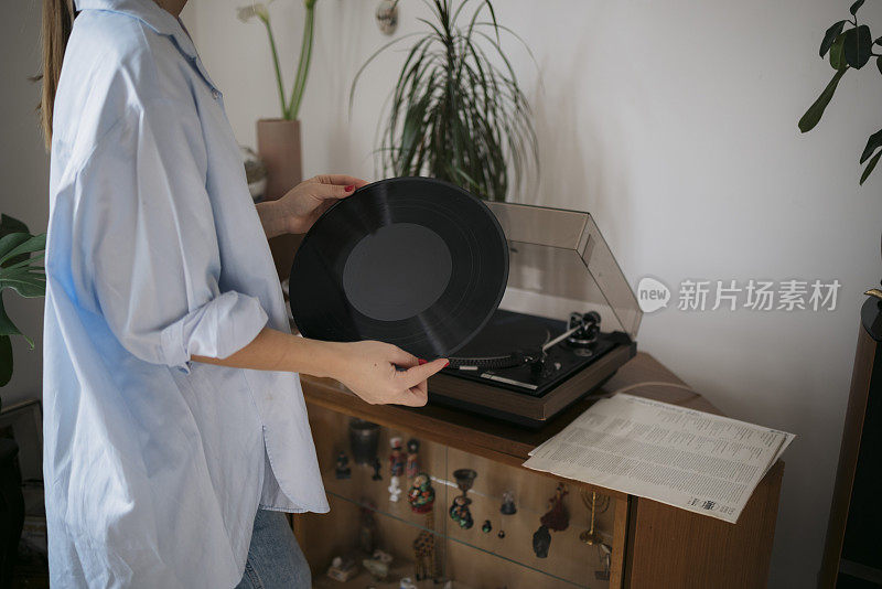 一个女人在家里用留声机播放黑胶唱片的特写