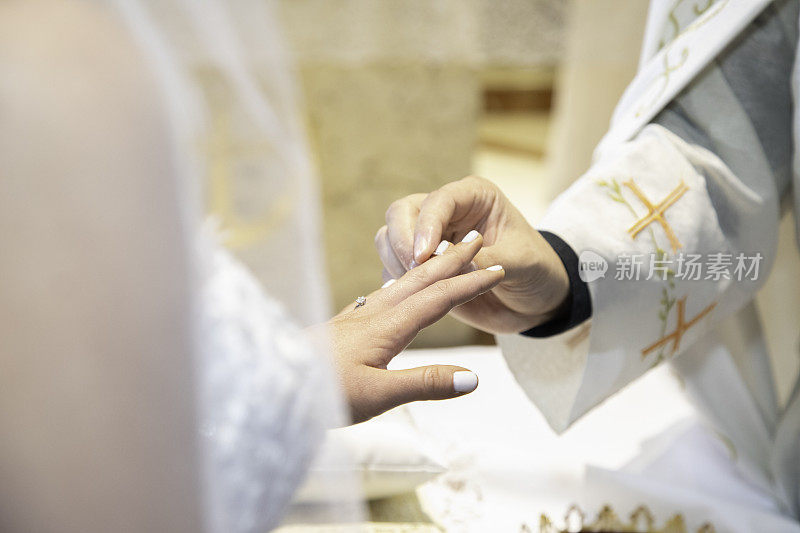 婚礼上，牧师把戒指戴在新娘手上