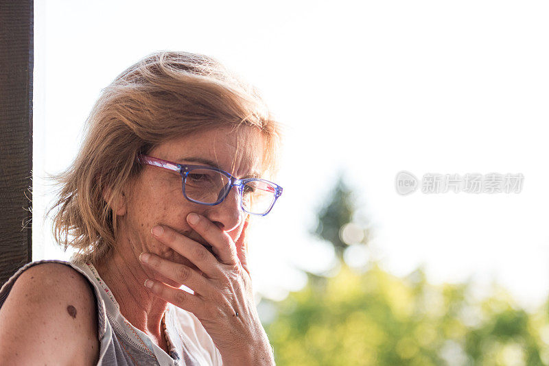 忧心忡忡的成熟女人坐在户外的头像