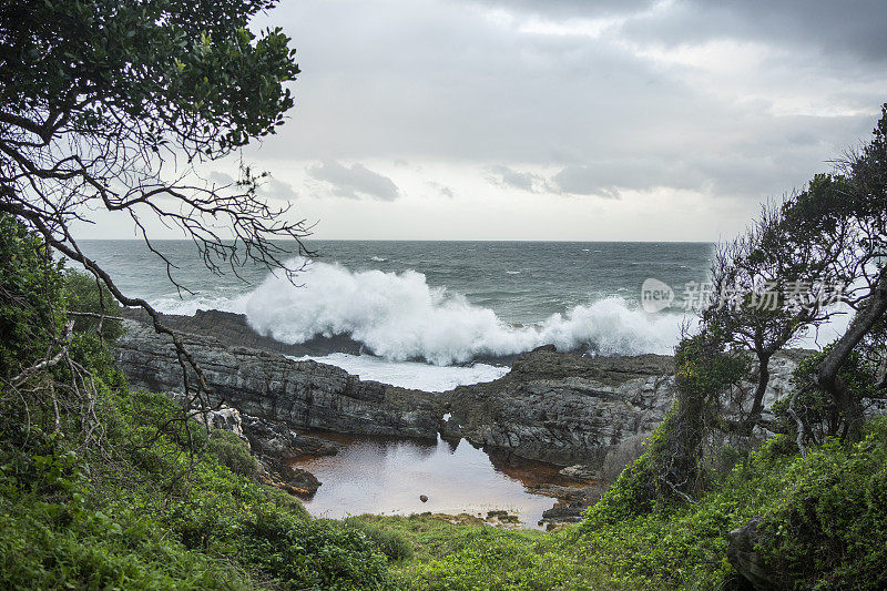 在一个阴天，海浪冲击着岩石嶙峋的海岸线