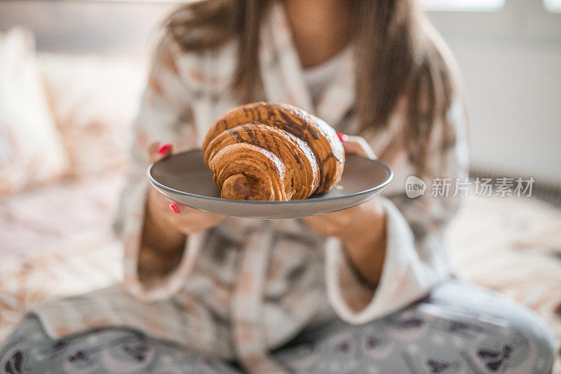 特写:盘子里的甜羊角面包被一个认不出来的女人端着