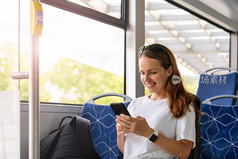 城市公共交通生活方式。一位女士在乘坐穿梭巴士时使用她的智能手机。