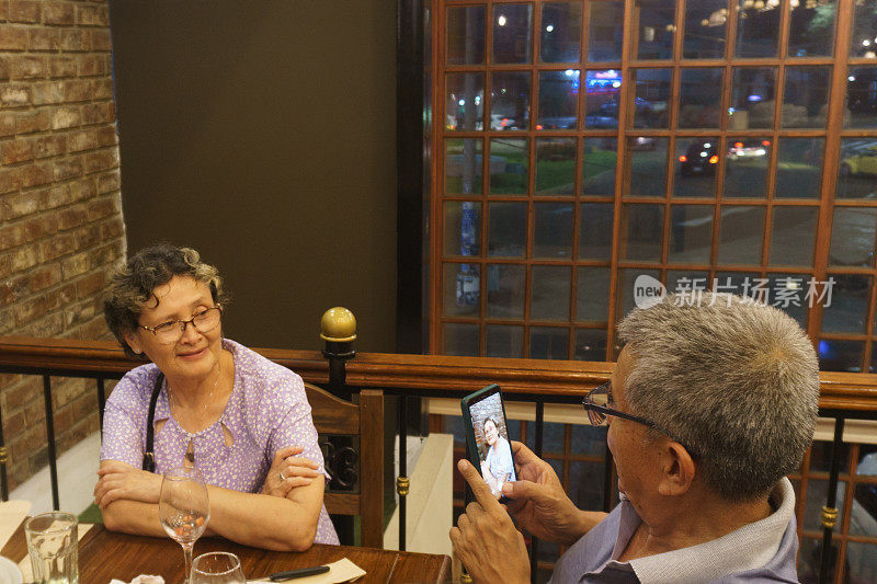一对老夫妇在餐厅用手机拍照