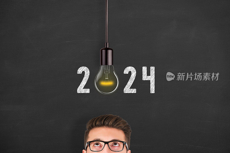 新年2024新想法新概念灯泡在人的头上在黑板背景