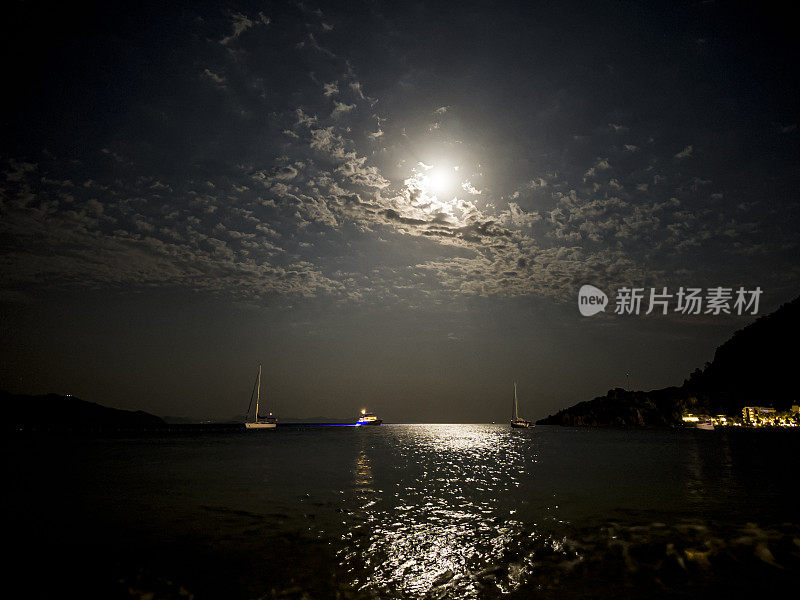 满月在繁星点点的夜空中升起，掠过大海和岩石峭壁。宁静、宁静和与自然统一的概念