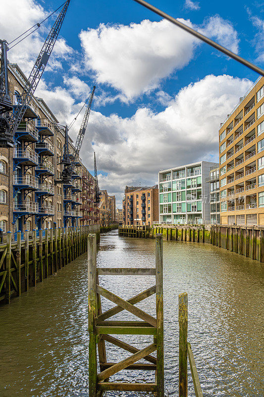 在英国伦敦的码头区，昔日的历史仓库现在被改造成房屋，沿河而建，就像一条运河，上面铺满了退潮时的绿泥和苔藓。