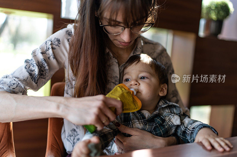 母亲正在给蹒跚学步的儿子喂奶