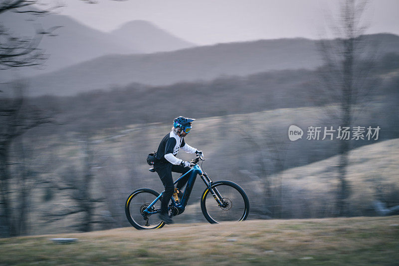 一名男子在日落时分骑山地自行车上山