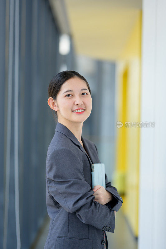 现代Z世代女商人在办公室里拿着数码平板电脑。放松，亚洲女商人在办公室用笔记本电脑工作。