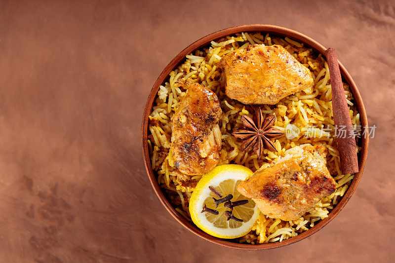 鸡肉印度香饭与印度香米，香料和柠檬在棕色背景，俯视图，复制空间