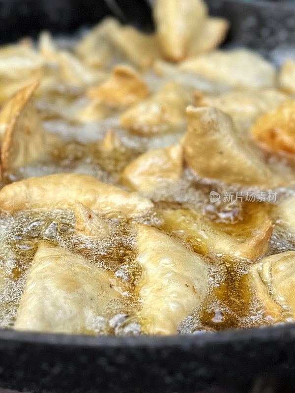 全画幅图像，在karahi(印度锅)中油炸的一批samosas，冒泡的热油，印度街头小吃摊，不健康的饮食，高架视图，聚焦于前景