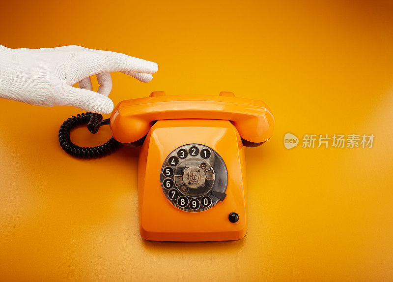 接到一个电话。拿着一个老式的电话听筒。一个橙色的复古电话接收机手持手持桔黄色的背景