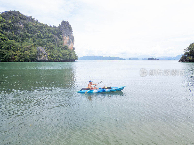 无人机拍摄的成熟男子在海湾里划皮艇的画面