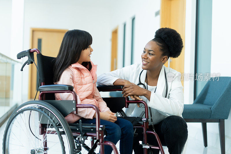 富有同情心的年轻医生和坐在轮椅上的小女孩在一起