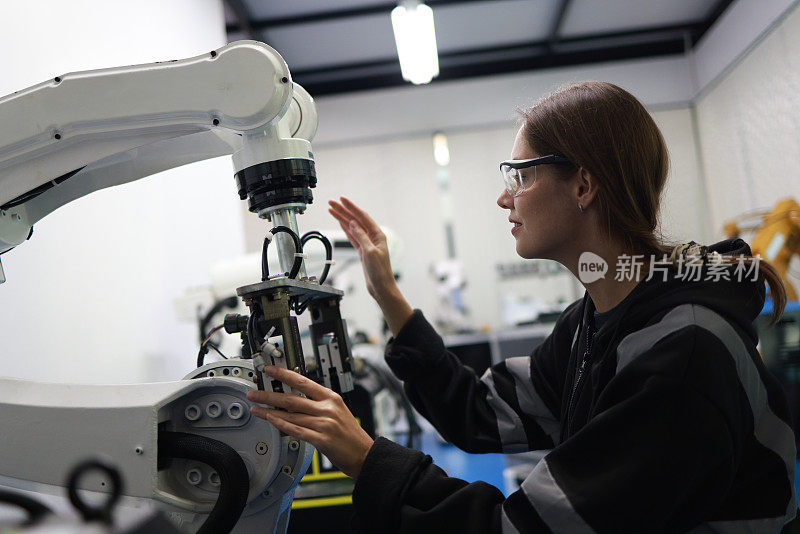 在一家制造焊接工厂的质量室里，一位女性机电工程师正在研究机械臂的原型，以检查新的程序设计