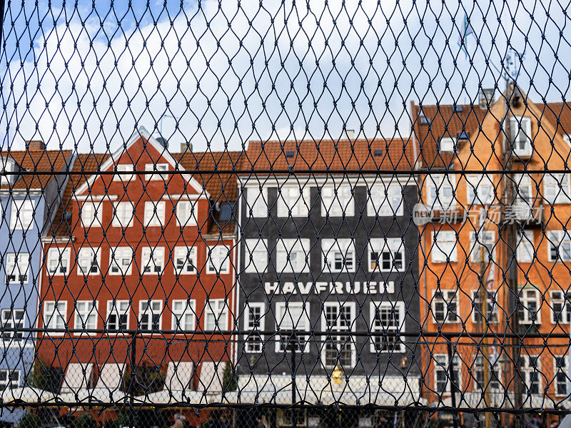 哥本哈根，丹麦——2022年10月9日:透过铁链栅栏，可以看到哥本哈根最受游客欢迎的部分，运河沿岸的古老建筑