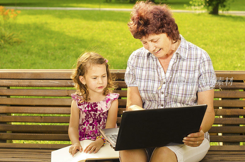 奶奶和孙女在公园里看笔记本电脑