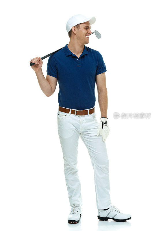微笑的高尔夫球手站着&拿着高尔夫球杆
