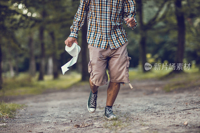 一个不认识的男人拿着卫生纸在森林里跑。