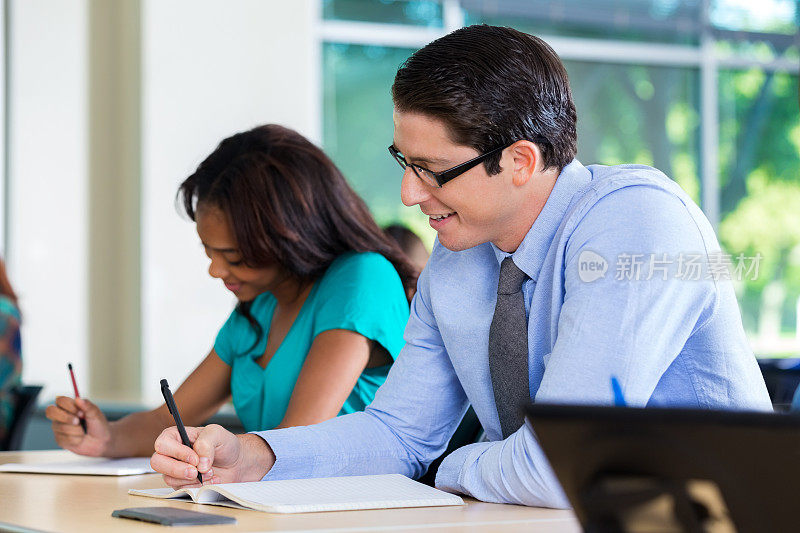 一个年轻人在大学课堂考试时做笔记
