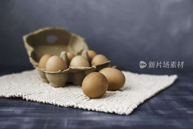 新鲜的棕色有机鸡蛋，鸡蛋盒在灰色设置