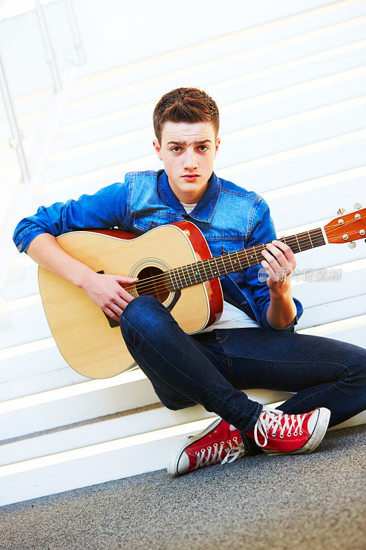 酷少年拿着吉他坐在楼梯上