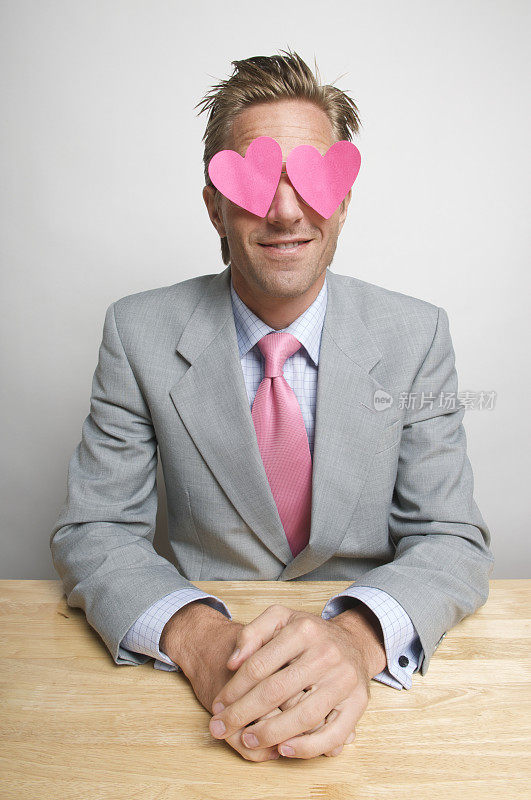 穿着粉色心形衣服坐在办公桌前的浪漫商人