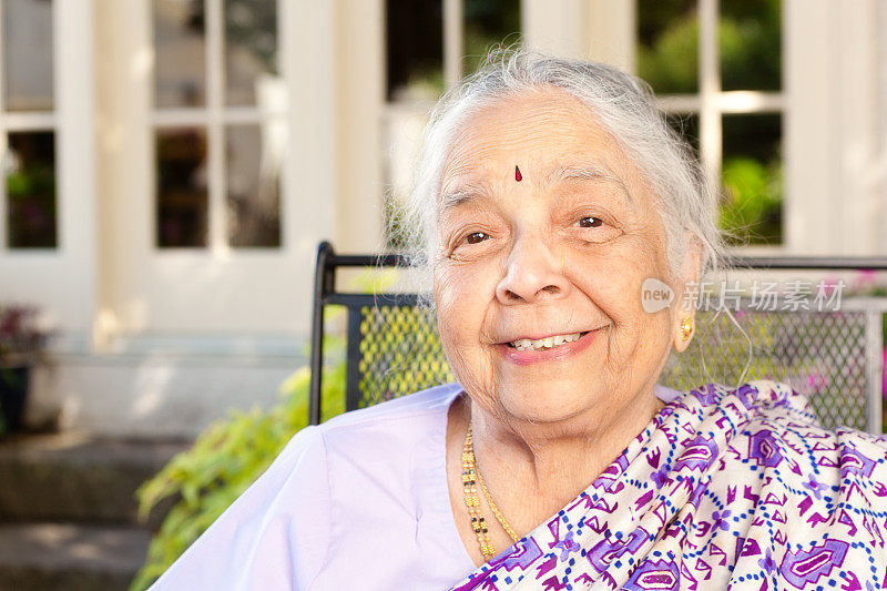 户外肖像的年长印度妇女在紫色纱丽