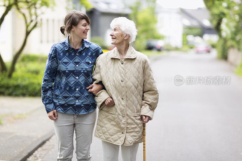 年轻的看护者帮助在街上行走的老年妇女