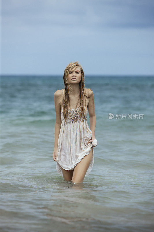 美丽的年轻女子时装模特穿着湿衣服在海洋