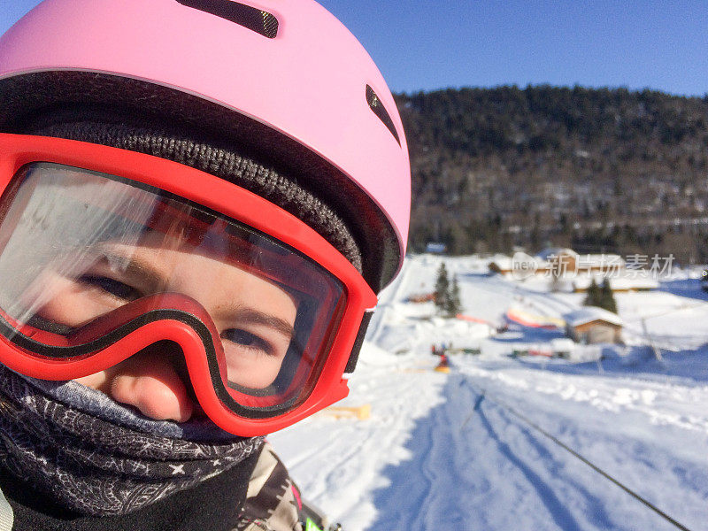 戴着粉色滑雪头盔和红色护目镜的爆头女孩