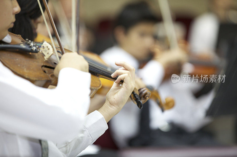 年轻的小提琴家小女孩在管弦乐队演奏。