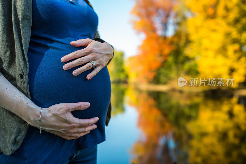 秋天在湖边抱着肚子的孕妇