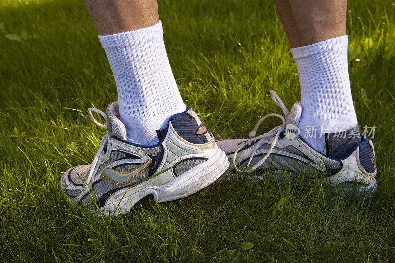 男人的脚在运动鞋和草
